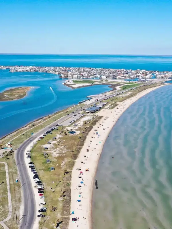 view of a narrow peninsula with a road, beachgoers, and surrounding waters - things to do south texas